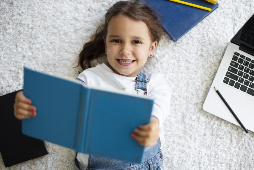 little girl holding a book and smiling